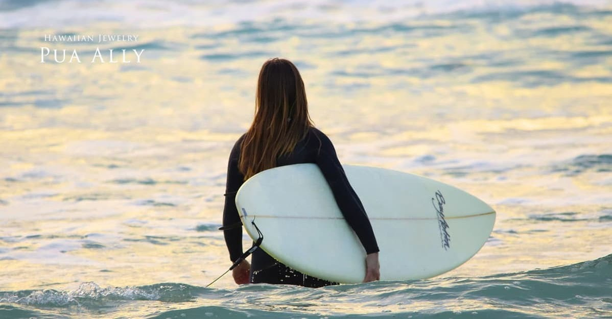 海の中に立つ女性サーファーの後ろ姿