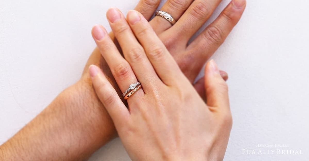 結婚指輪を着けた男性の手に重なる結婚指輪と婚約指輪を着けた女性の手
