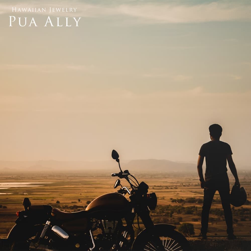 アメリカの風景に男性とバイクが映っている写真　男性はバイクの横に立っていてヘルメットを手に持っている