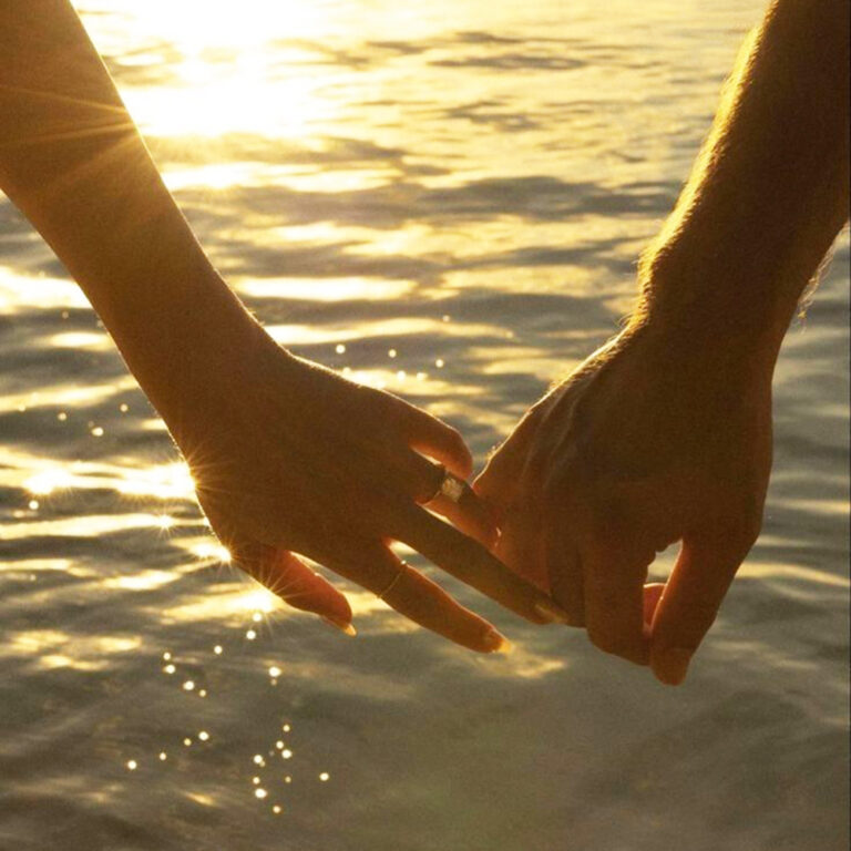 海辺でカップルが手をつなぐ