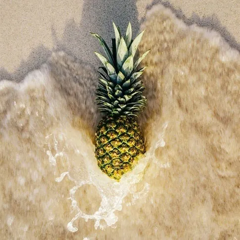 砂浜にあるパイナップルの画像