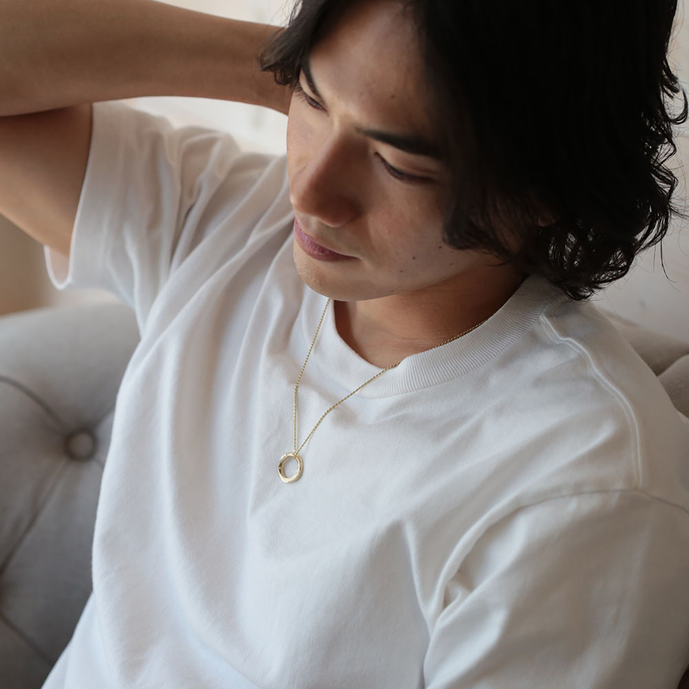 サークルのネックレスを着けた男性が頭を掻く仕草をしている画像