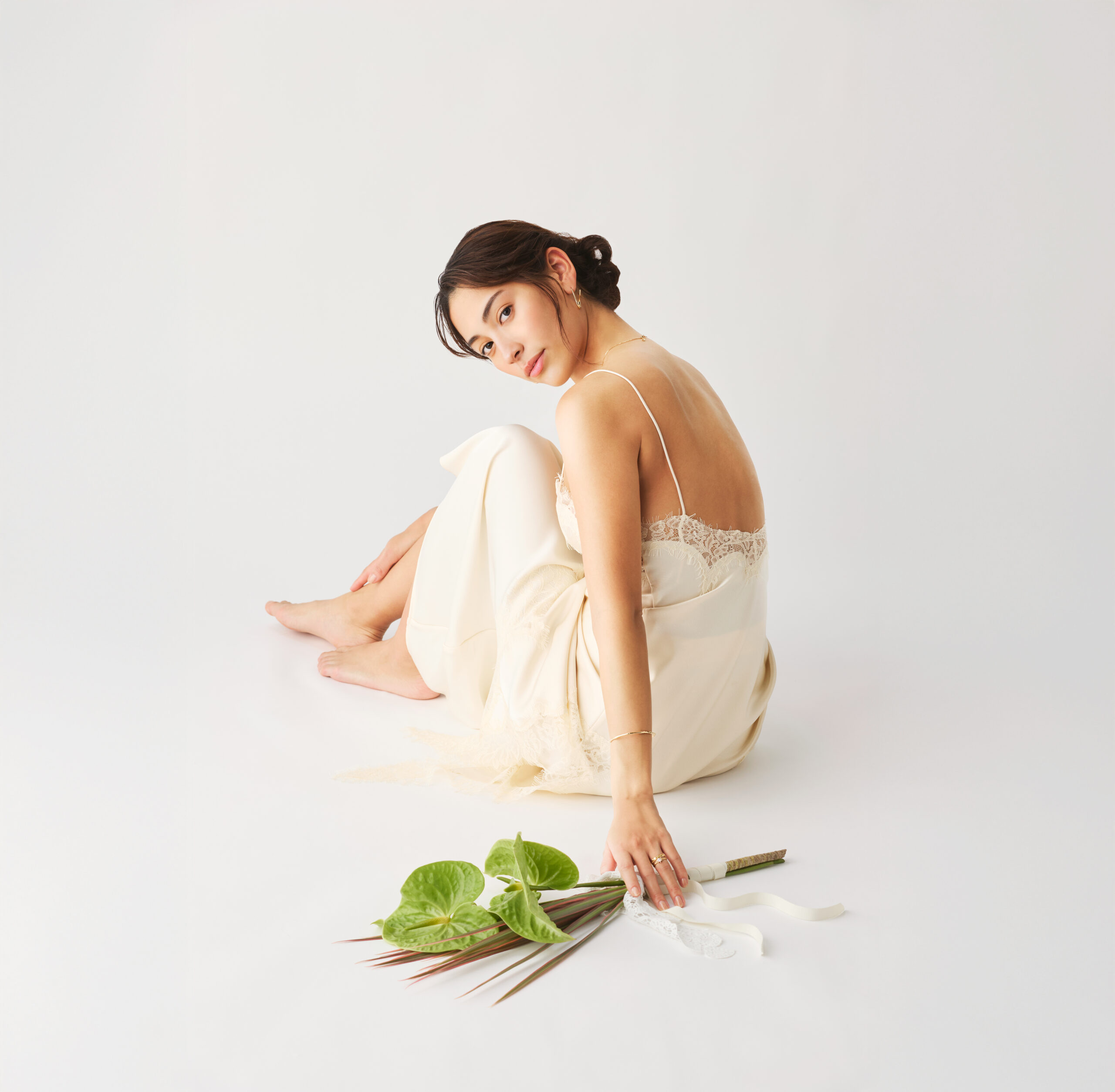 白いドレスを着用した女性がグリーンのブーケを持っている