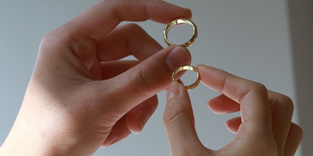 ハワイアンジュエリーの結婚指輪を掲げるカップルの手元